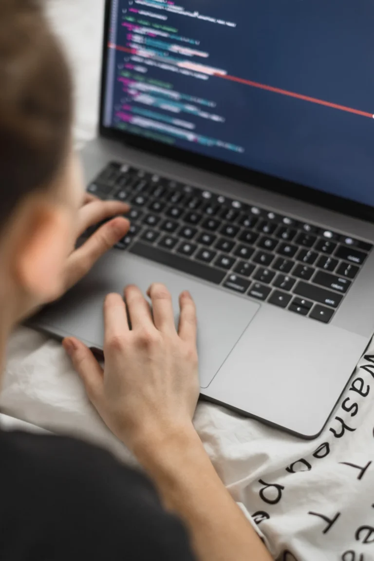 Young female programmer writes program code on a computer laptop in the bed at home. remote work