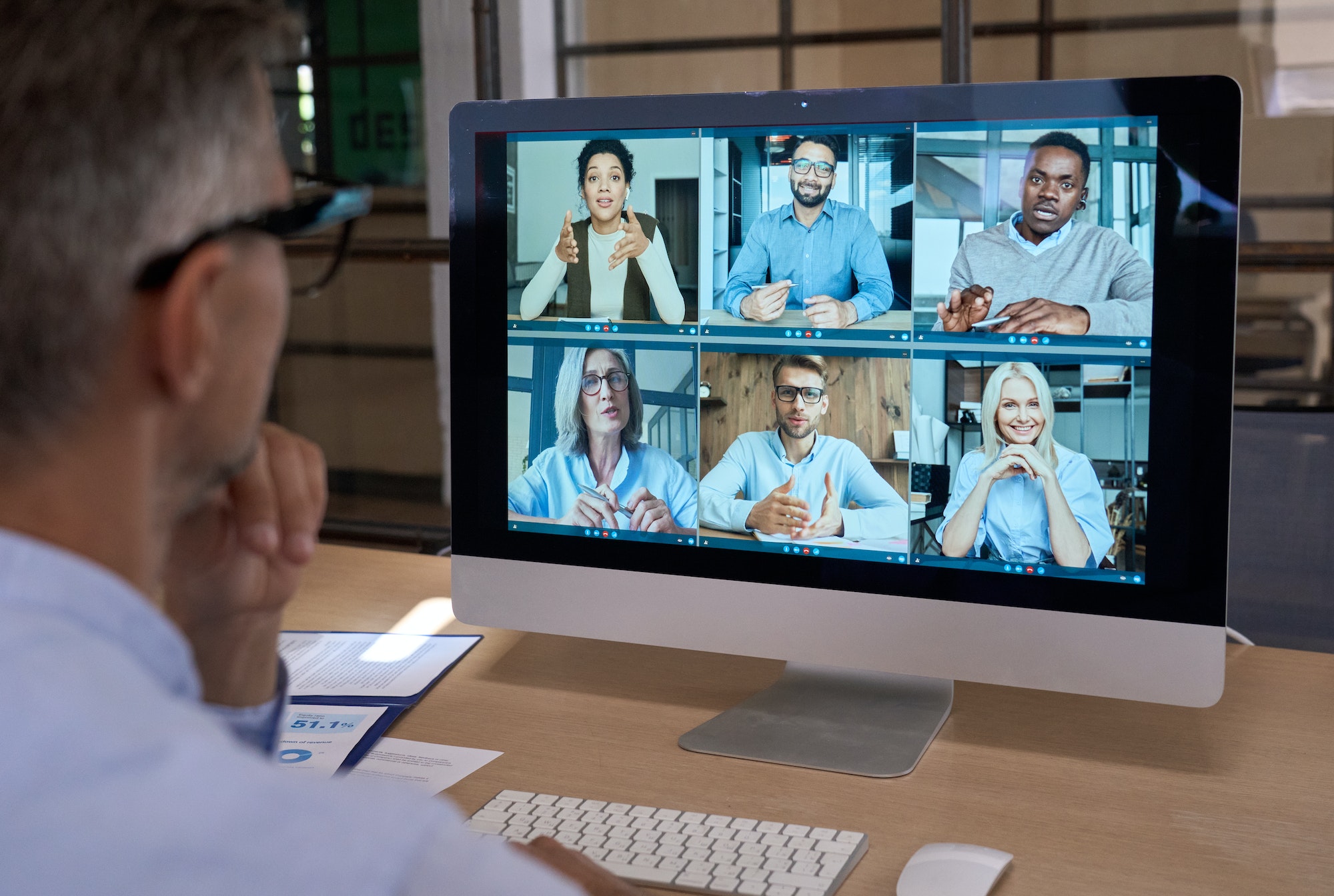 Businessman talking with team leading virtual meeting on computer. Over shoulder
